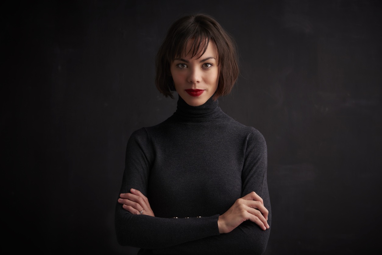 Beautiful young woman wearing red lipstick while posing at dark background