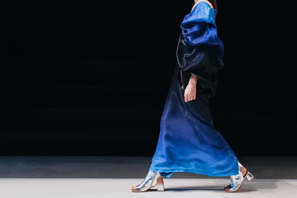 A model walking on a catwalk, strutting a blue designer dress