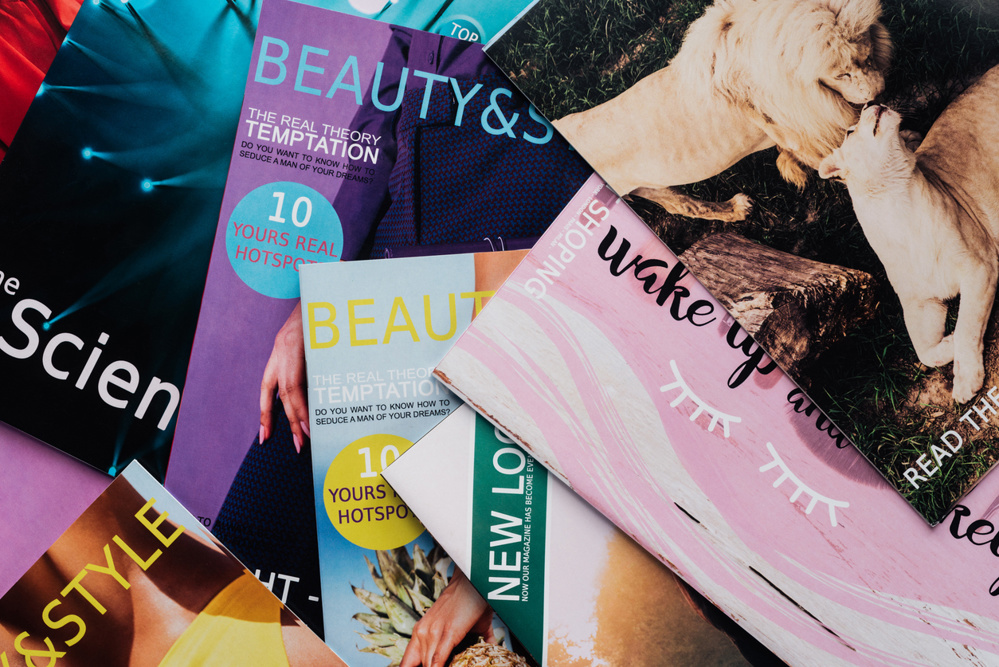 Top view of pile of different tabloid magazines on surface