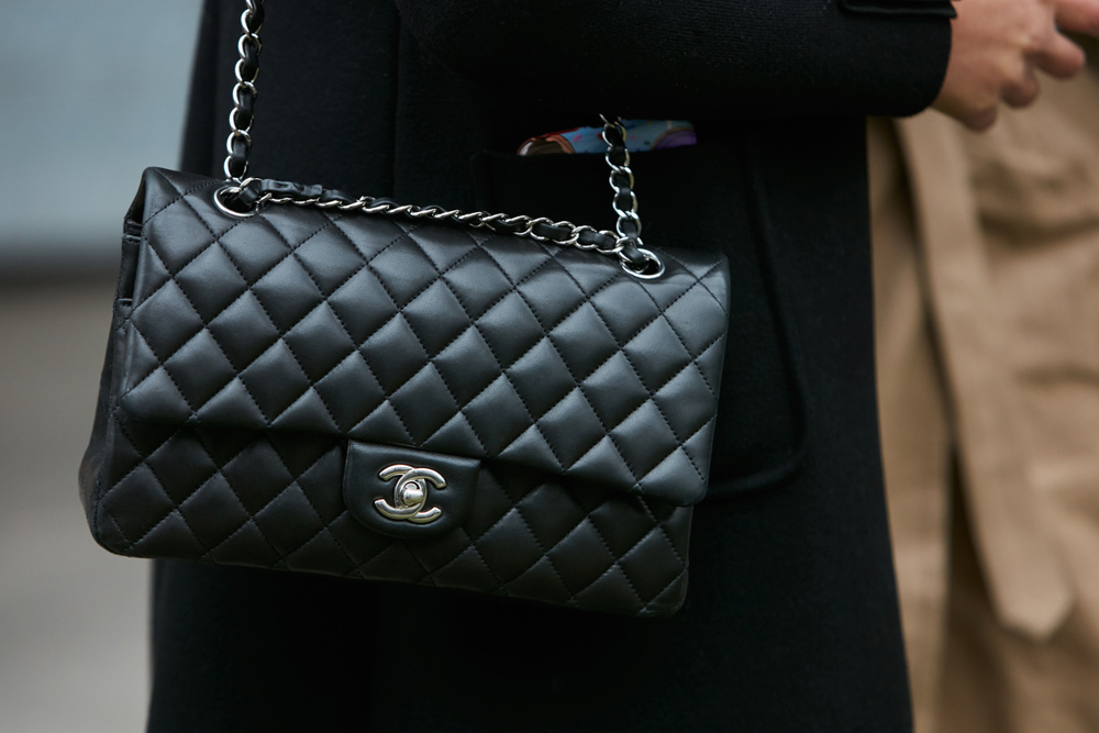 MILAN - JANUARY 15: Woman with black Chanel leather bag with silver chain before Giorgio Armani fashion show, Milan Fashion Week street style on January 15, 2018 in Milan