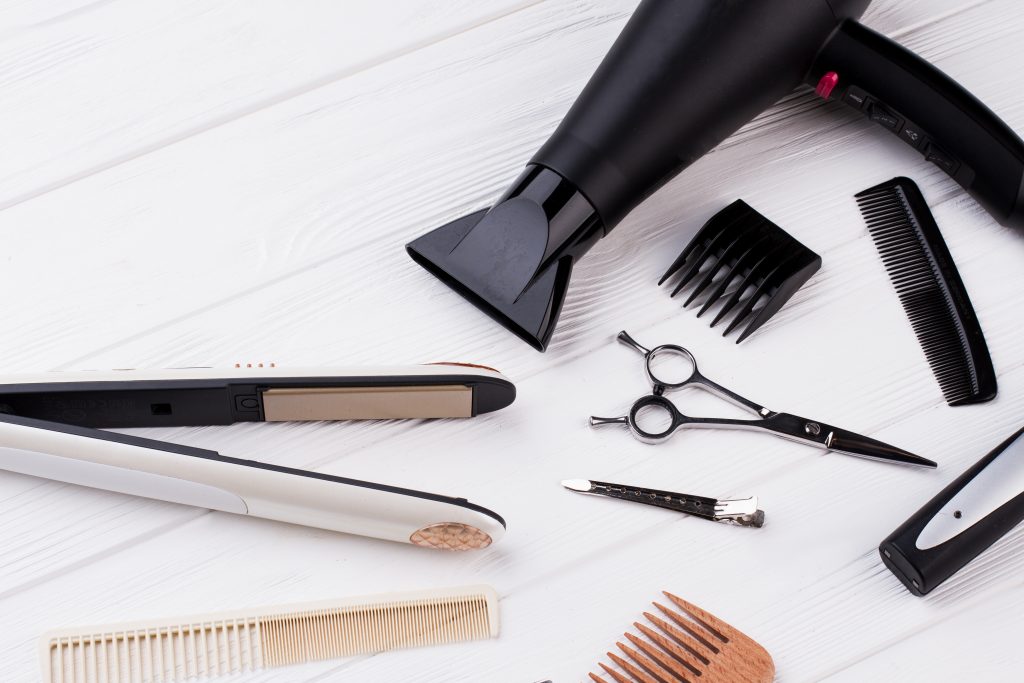 Hairdresser tools and accessories on wooden table.