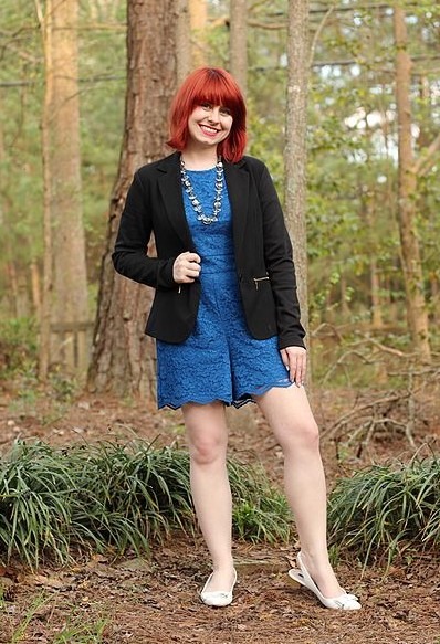 A woman wearing a blue lace romper and a black blazer