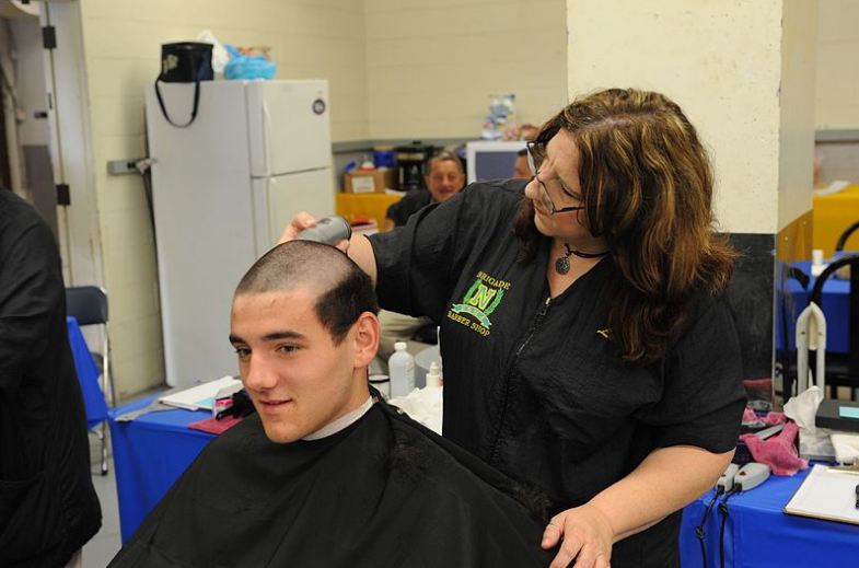 A freshly inducted military personnel getting their induction haircut.