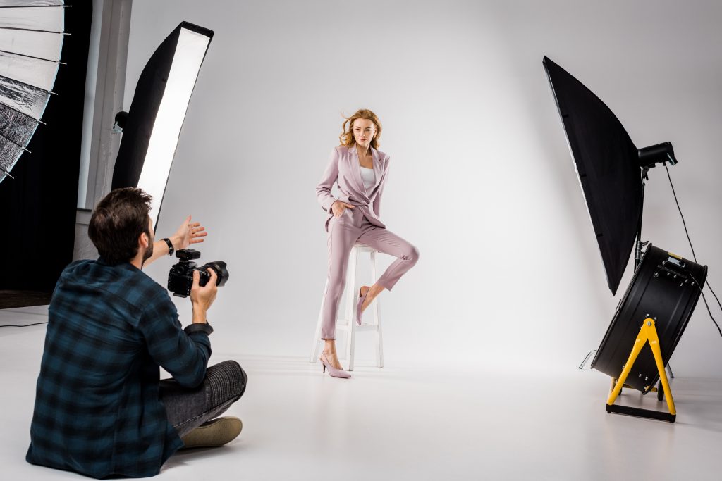 young photographer shooting beautiful stylish young woman in photo studio