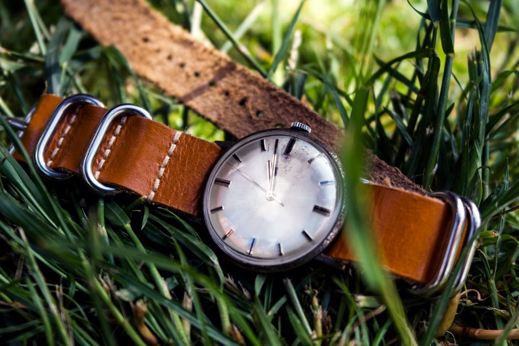 Vintage watch in the grass with a nato strap made out of leather light brown
