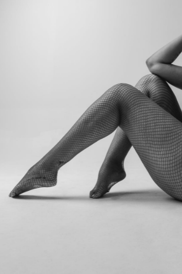 anonymous-woman-in-fishnet-stockings-sitting-on-floor-in-studio