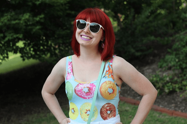 red-haired woman wearing sunglasses and a colorful donut print tank top
