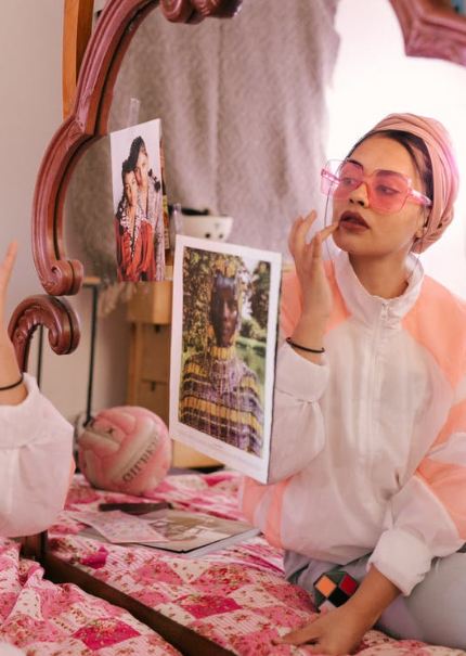 a woman doing makeup in front of a mirror