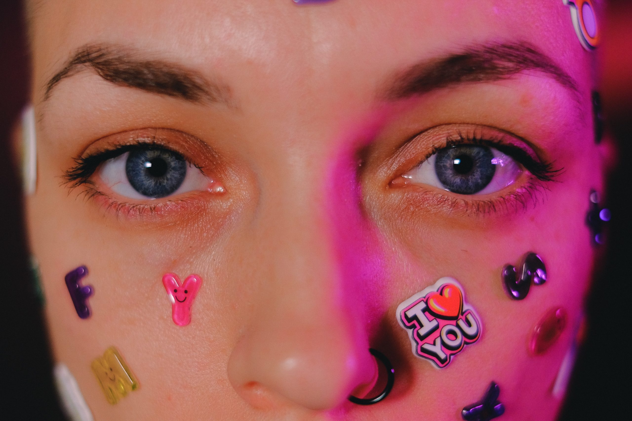 a close up of a woman with a nostril piercing and stickers on her face
