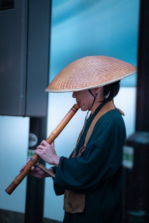 a person wearing a handwoven hat, playing a flute
