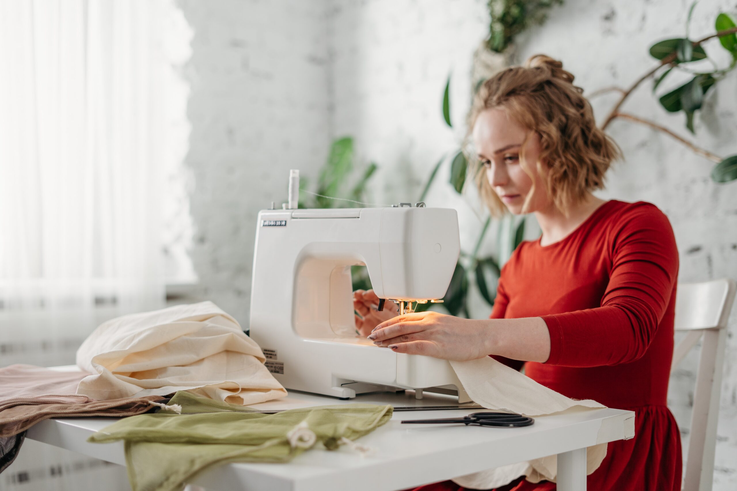 a-woman-using-a-sewing-machine-working-on-a-table-with-fabric