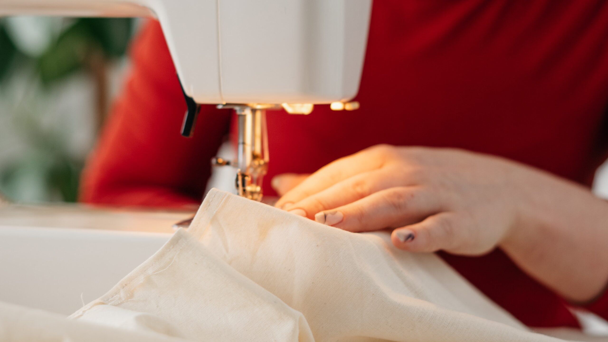 the-hand-of-a-person-in-a-red-ress-stitching-a-fabric-using-a-sewing-machine