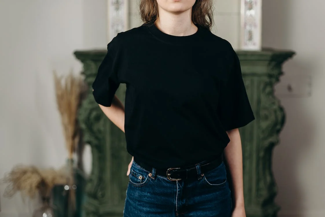 a person wearing a black t-shirt and denim jeans