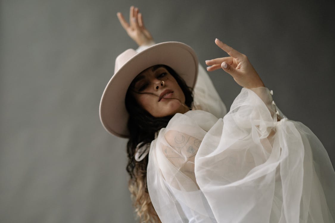 a woman in see-through long sleeves and a hat dancing