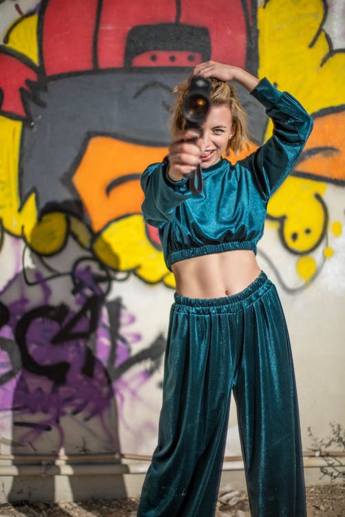 a young woman in a matching clothing set posing on the background of a wall with graffiti