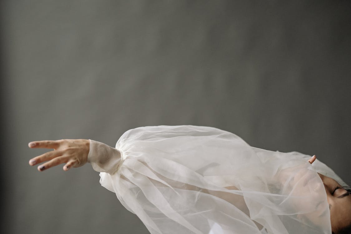 an extended arm of a woman in white chiffon long sleeves