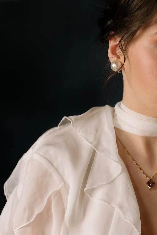 woman in a white dress wearing pearl earrings