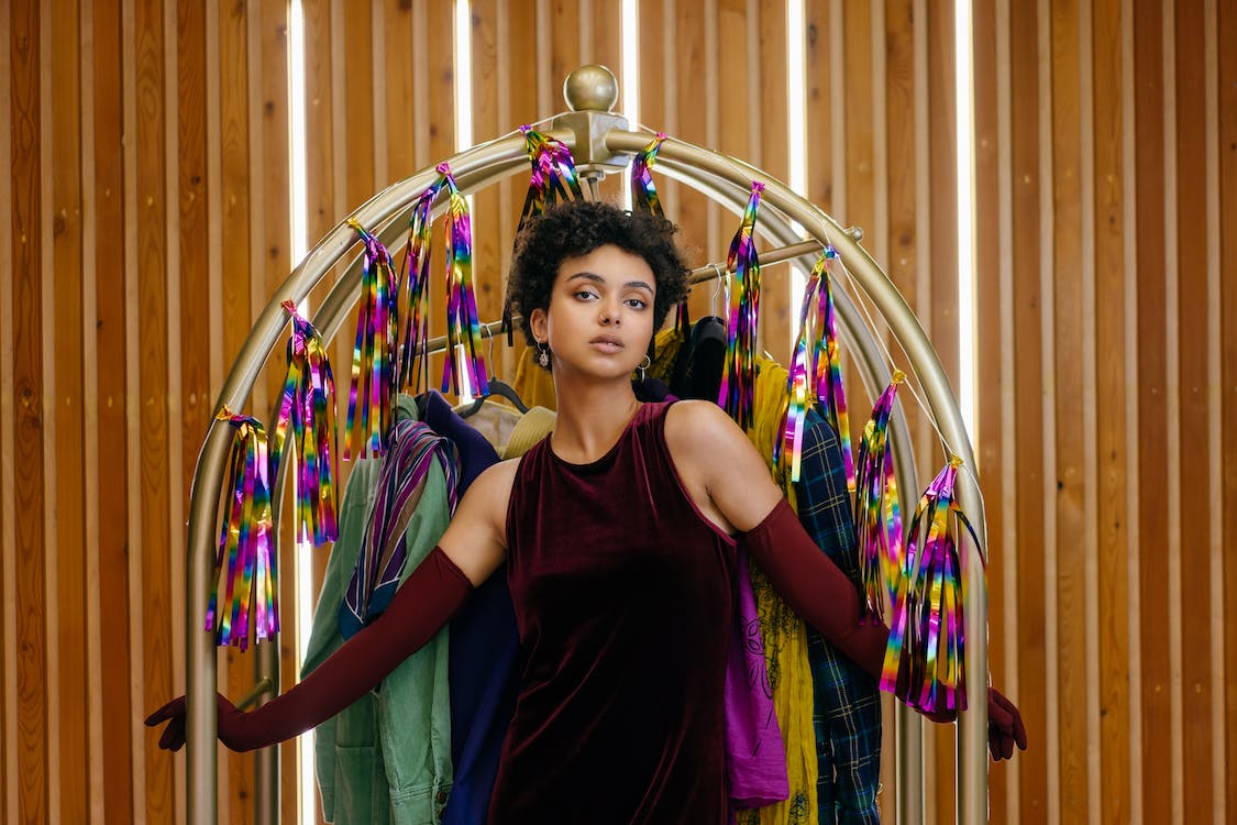 woman wearing a maroon dress posing in front of a clothes rack