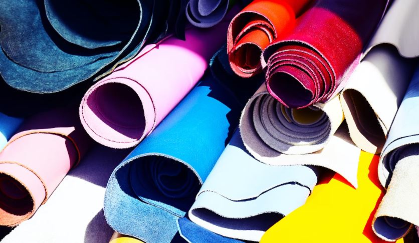 Collection of fabric of various colors lying on wooden table inside workshop of leatherworker