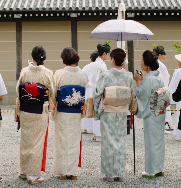 Group of people wearing white and yellow floral kimono standing on gray concrete floor during daytime 