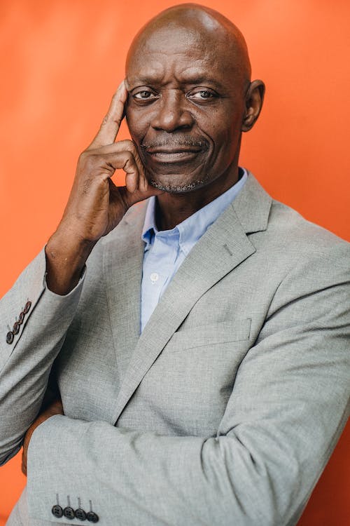 Intelligent black businessman in suit on orange background
