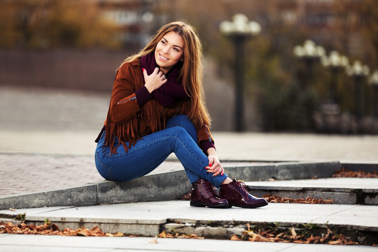 woman in suede leather jacket sitting on city sidewalk